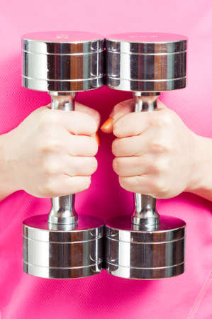 Closeup of chromed dumbbells or weights in female hand for strength and bodybuilding conceptの写真素材