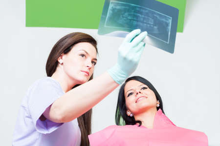 Female dentist doctor and woman patient checking teeth xrayの写真素材