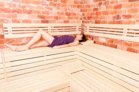 Beautiful woman lying on back on wooden bench in salt sauna as healthy lifestyle conceptの写真素材