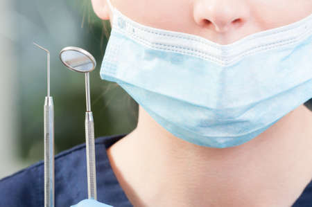 Closeup of stainless dental tools hold by female orthodontist in dental office as dentistry...