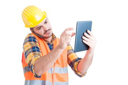 Handsome engineer with helmet is talking on the phone and holding a tablet in multitasking mode for...