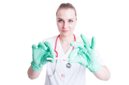 Smoke addiction concept with female doctor holding a cigarette in white coat and gloves isolated on white backgroundの写真素材