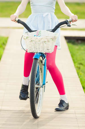 Close-up view of woman standing on a blue vintage bike as summertime activity concept
