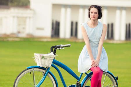 Summer activity concept with attractive woman standing on vintage bicycle outsideの写真素材