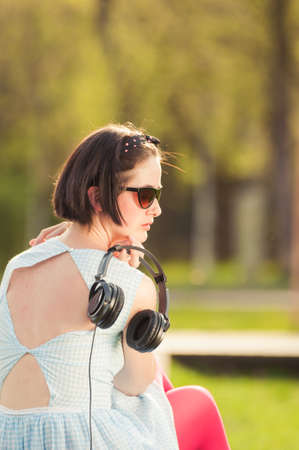 Close-up of young hipster woman with headset outside in the park listening to musicの写真素材