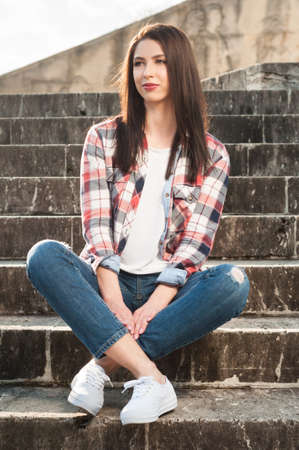 Young beautiful girl resting on the park stairs in warm spring dayの写真素材