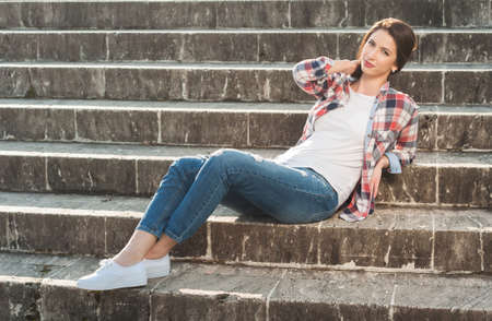 Beautiful young girl posing on stone stairs wearing casual clothes and resting as leisure conceptの写真素材