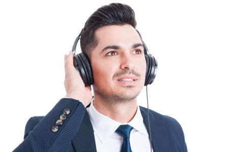 Close-up portrait of handsome businessman with headphones listening to music and looking up ...