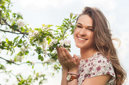 Young beautiful woman in blooming garden enjoying freetime and relaxing in the natureの写真素材