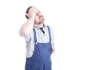 Unhappy repairman with closed eyes touching his forehead looking tired with copy space isolated on white backgroundの写真素材