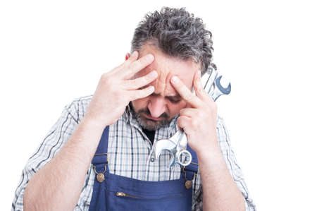 Closeup portrait of young mechanic under pressure having head ache as stressful job concept isolated on whiteの写真素材