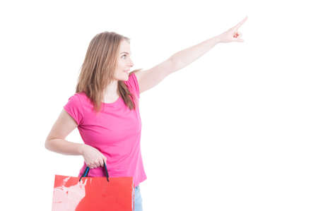 Side portrait of smiling beautiful woman doing shopping and pointing finger up isolated on white background with copyspaceの写真素材