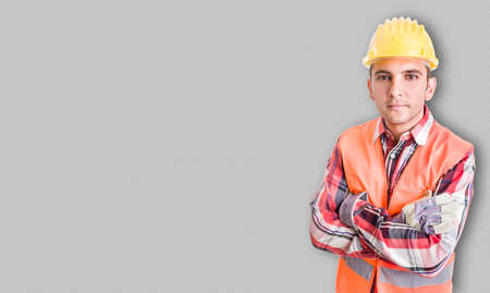 Portrait of handsome constructor with protection equipment and helmet standing with arms crossed...