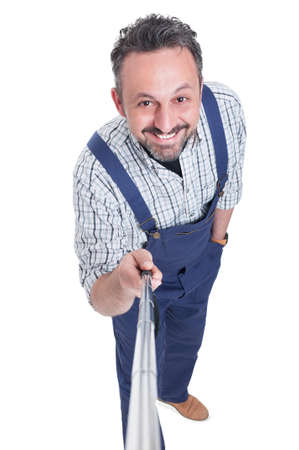Top view of cheerful attractive mechanic man taking photo with selfie stick isolated on white studio backgroundの写真素材