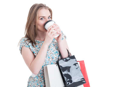 Young shopaholic drinking hot coffee in her break and doing shopping isolated on white background with copy space areaの写真素材
