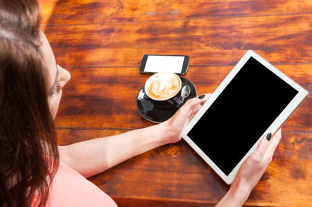 Woman holding tablet with coffee and smartphone with blank screen using modern technology with copy text spaceの写真素材