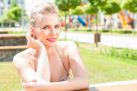 Beautiful woman sitting smiling and posing outside in park in sun light with copy text spaceの写真素材