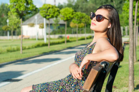 Girl wearing sunglasses posing outside in park in sunlight with advertising copy spaceの写真素材