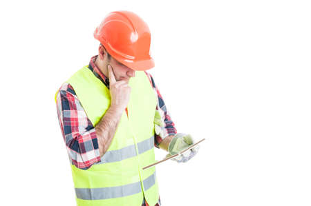 Constructor in safety equipment with modern tablet thinking at something isolated on white background with text areaの写真素材