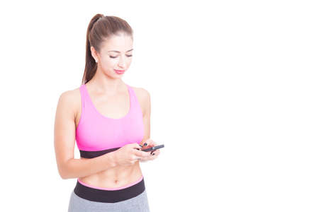 Fit lady wearing sportswear holding telephone and texting isolated on white background with copy advertising areaの写真素材