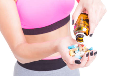 Close-up of woman at gym spilling bottle of pills or supplements isolated on white backgroundの写真素材