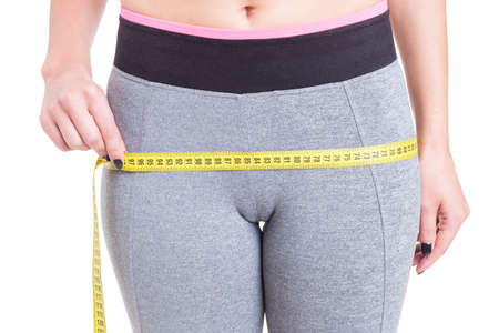 Close-up of female measuring booty with tape line at gym isolated on white background