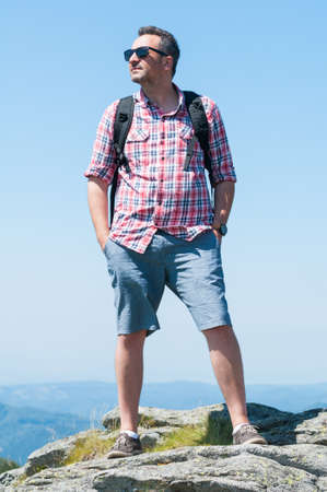 Man on top of the mountain looking away relaxed in sunlight with blue skyの写真素材