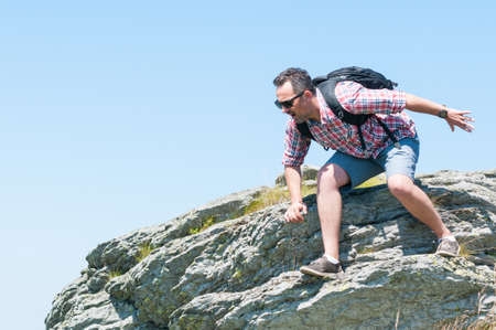 Male backpacker falling or jumping from cliff outside on top of the mountain with copy space
