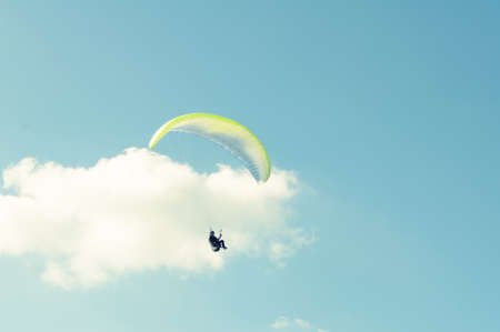 Paraglider with white wing turning around in the blue sky with copy text spaceの写真素材
