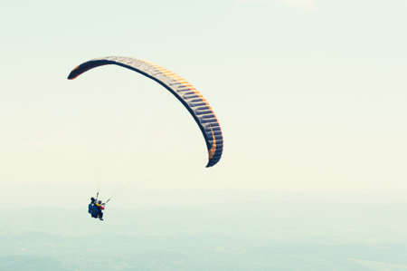 Tandem flight over the green hills on sunny day with copy advertising areaの写真素材