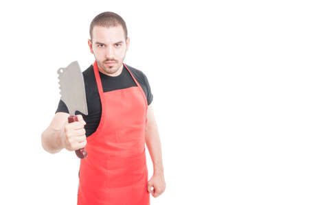 Serious male butcher in red apron showing meat chopper on white background with advertising areaの写真素材