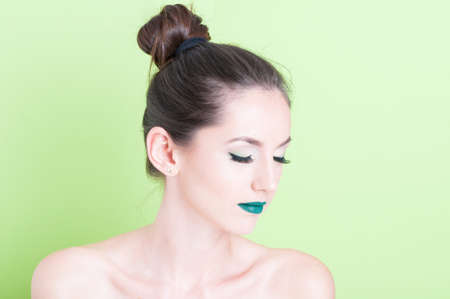 Woman posing with professional green trendy make-up isolated on green background with copy text areaの写真素材