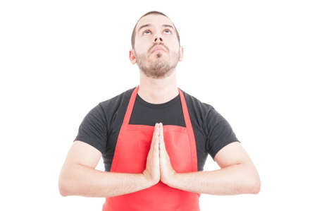 Handsome supermarket employee praying for luck or a miracle isolated on white backgroundの写真素材