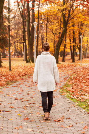 Fall relaxation concept with female walking on the park alleyの写真素材