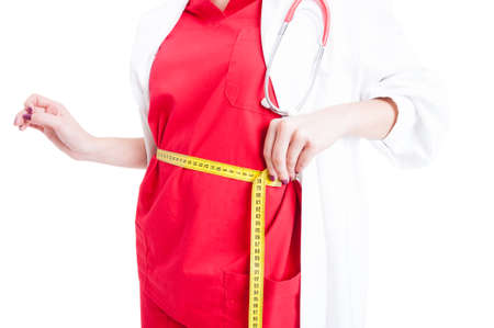 Closeup of female doctor measuring her waist with measuring tape as weightloss concept on white backgoundの写真素材