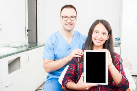 Orthodontist and patient holding tablet and smiling as being friendly and trustworthyの写真素材