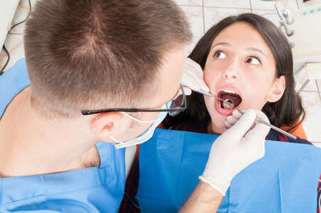 Girl sitting in dentist chair having a consultation from doctor with special toolsの写真素材