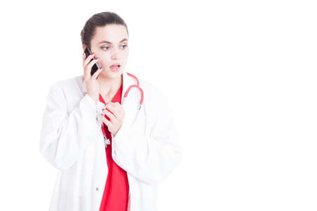 Serious medic female with medcial uniform having a conversation on mobile phone isolated on white with copyspaceの写真素材