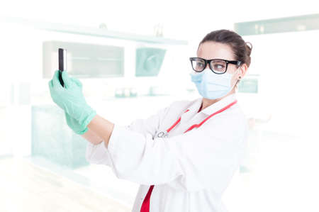 Attractive young medic in medical equipment with smartphone taking selfportraitの写真素材