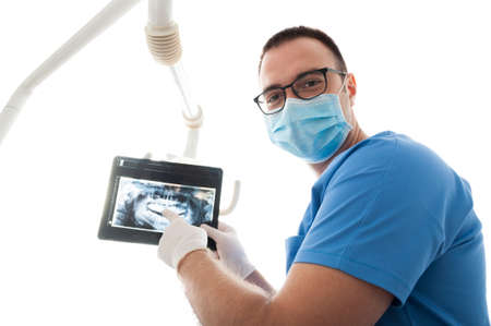 Young dentist wearing mask showing x-ray exam in bright light and smilingの写真素材