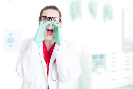 Beautiful female doctor screaming out loud in her office with copy spaceの写真素材