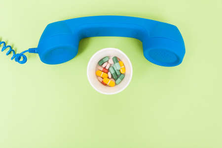 Medical appointment concept with vintage phone and vitamins capsules and pills on green background with text areaの写真素材