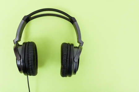 Modern headphones on green background in close-up with advertising area as digital technology or music conceptの写真素材