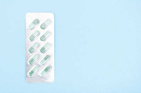 One blister full with green capsules isolated on blue background with copy advertising areaの写真素材