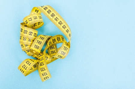 Weight loss concept with yellow centimeter isolated on blue background with advertising areaの写真素材
