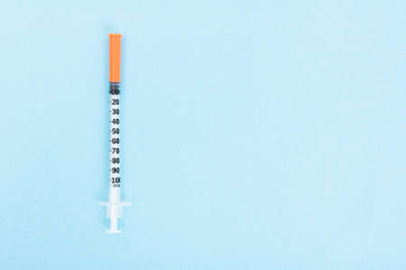 Medical syringe in closeup view on blue background with text area as clinical treatment conceptの写真素材