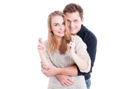 Attractive couple hoping or wishing with fingers crossed isolated on white backgroundの写真素材