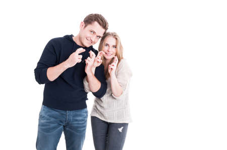 Attractive couple showing fingers crossed and smiling isolated on white background with copy text spaceの写真素材