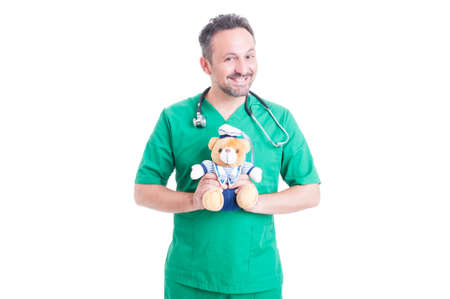 Pediatrician doctor in medical uniform with plush teddy bear smiling friendly on white backgroundの写真素材