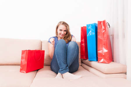 Shopaholic lady sitting on couch acting happy with shopping bags around like being joyful
